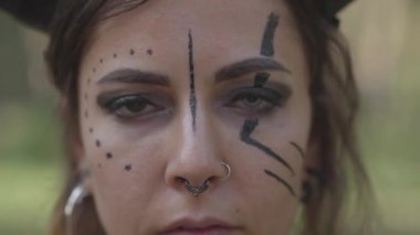 Farklı renk gözleri ve kameraya bakarak burnunu piercing ile çekici kadının yakın çekim portre. Ormanda dansçı performansı. Yavaş çekim.