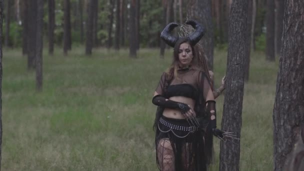 Young women in theatrical costumes of forest dwellers or devils showing perfomance in enchanted forest or making ritual — Stock Video