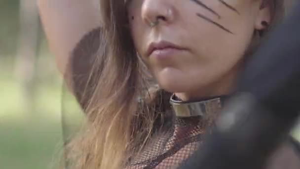 Retrato de cerca del hada atractiva del bosque con grandes cuernos negros en la cabeza, ojos de diferentes colores y largas garras en los dedos bailando bajo los árboles. El antiguo ritual de la criatura del bosque — Vídeos de Stock