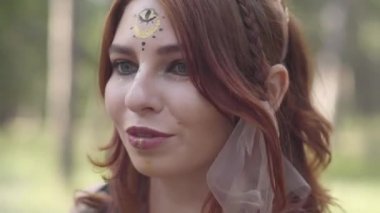 Orman perisi kostümü içinde kafasına dalları çelenk ile güzel genç kadın ya da performans gösteren ormanda dryad dans performans gösteren veya ritüel yapma. Vücudunu okşayan kız. Kamera aşağı hareket ediyor