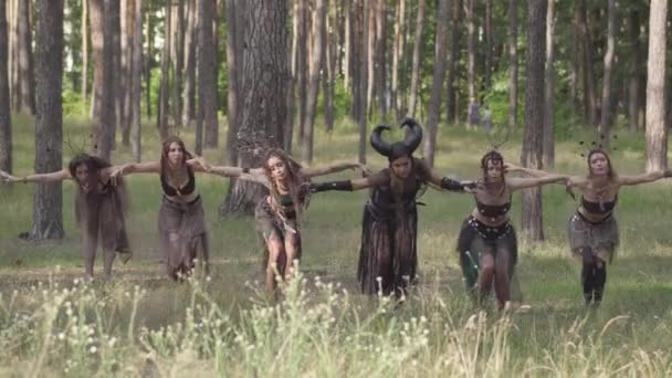 Fiatal nők színházi jelmezek az erdők lakói, vagy ördögök táncolnak erdőben bemutató teljesítési vagy hogy rituális — Stock videók