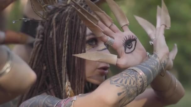 Attractive dryad or forest fairy with afro-braids and tattoos on the arm moving fingers with false long claws on. The ancient ritual of forest creatures. Performance of dancers in forest — Stock Video