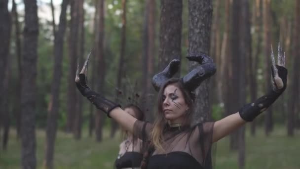 Jeunes femmes en costumes de théâtre d'habitants de la forêt ou de démons montrant la parfumerie dans une forêt enchantée ou faisant un rituel 