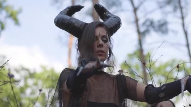 Mujer joven en trajes teatrales de diablo o danza maléfica en el bosque mostrando perfomance o haciendo ritual — Vídeo de stock