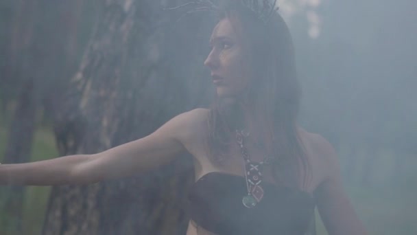 Молодые женщины в театральных костюмах лесников или дьяволов, танцующих в лесу, демонстрируют перфоманс или совершают ритуал в облаке дыма . — стоковое видео