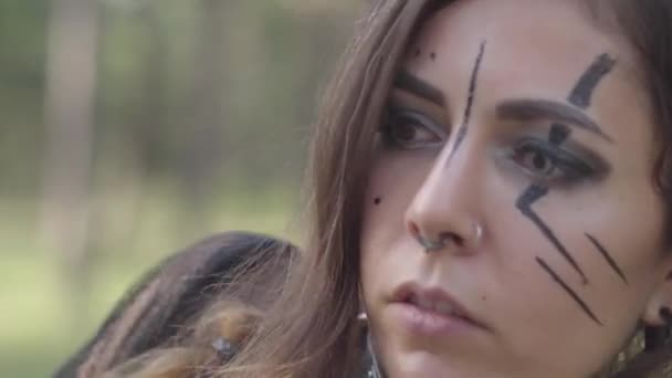 Retrato de cerca del hada atractiva del bosque con grandes cuernos negros en la cabeza, ojos de diferentes colores y largas garras en los dedos bailando bajo los árboles. El antiguo ritual de la criatura del bosque — Vídeos de Stock