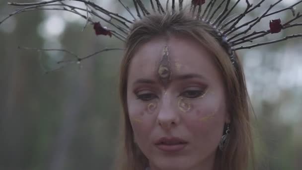 Retrato de um dryad atraente ou fada da floresta com uma coroa de ramos na cabeça e pintou o terceiro olho na testa dançando sob as árvores. Ritual antigo da criatura da floresta. Movimento lento . — Vídeo de Stock