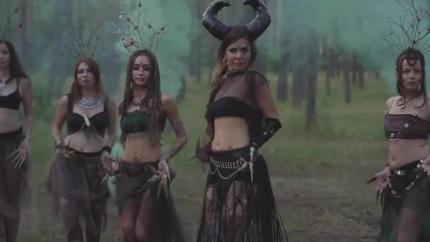 Mladé ženy v divadelním kostýmech pro lesní obyvatele nebo ďábly, které vykazují parfém v začarovaným lese a tančící břišní tanec. Zpomaleně. — Stock video