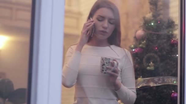 Cerrar Video Mujer Pie Puerta Cristal Árbol Navidad Hablando Por — Vídeo de stock