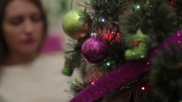 背景模糊的女孩装饰圣诞树 在前景特写许多五颜六色的灯光闪烁的圣诞树 — 图库视频影像