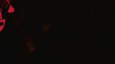 Bulanık, odaklı olmayan konser videosu, sahnede çalan bando, bacakların kısmi görünümü 