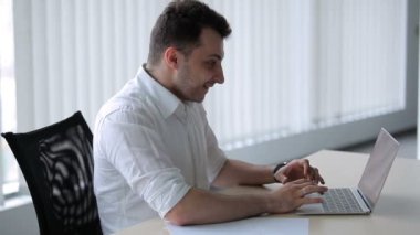 Genç adam dikkatle laptoptan izliyor ve sevinmeye ve ışıldamaya başlıyor. Yönetici Plaing çevrimiçi ofiste.