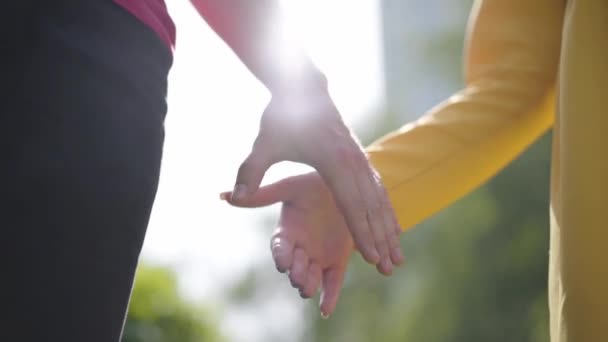 Roztomilá šťastná dvojice s láskou chodí po parku a jemně se drží za ruce v jarním hezkým dnu. Close-up. — Stock video