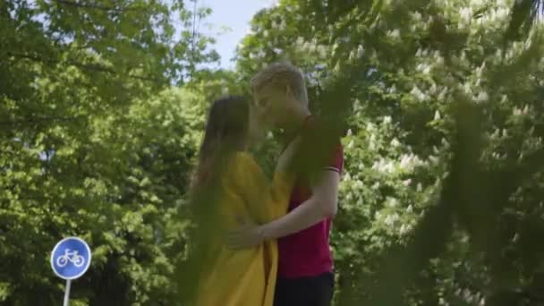 Bonito casal caucasiano no amor ternamente abraçando e sorrindo no fundo do parque de primavera verde. Data de jovem belo homem e mulher. Romântico passar tempo ao ar livre . — Vídeo de Stock