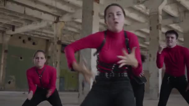 Des danseuses et des garçons habiles jouissant de mouvements hip hop exécutant ensemble des danses freestyle dans un bâtiment abandonné. Caucasien bande faire moderne freestyle danse à l'intérieur .