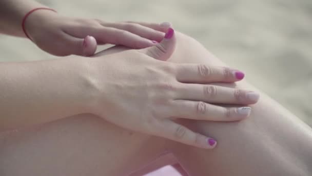 Weibliche Hand, die Sonnenspray auf ihre Beine aufträgt, um sich am Strand in Großaufnahme zu sonnen. Sommerfreizeit. Körperpflege — Stockvideo