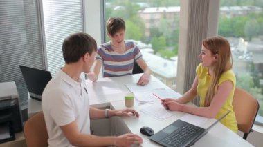 Erkekler ve kadınlar ofiste konuşuyorlar. Erkekler ve kızlar gülümsüyor. Gençler kameraya dönüp el sallamaya ve gülümsemeye başlıyor..