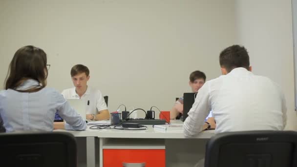 两个男人坐在一个男人和一个女孩面前 办公室里有一张大桌子 穿着条纹T恤的人一边说 一边用手拿着手势 — 图库视频影像