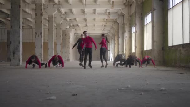 Compétence danseurs professionnels filles et garçons appréciant les mouvements hip hop exécutant la danse freestyle ensemble dans un bâtiment abandonné. Caucasien bande faire moderne freestyle danse à l'intérieur . — Video