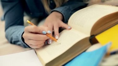 Closeup güzel öğrenci açık havada kalem ile kitap okuma, Uzun saçlı sarışın öğrenci parkta kampüs çim üzerinde battaniye üzerinde yatıyor, video