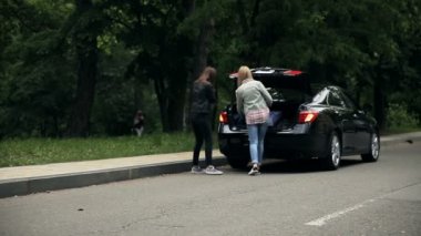 Çekici kızlar bagajı açar ve güzel sarışın kırmızı acil durum levhasını yola koyar çünkü araba bozuktur..