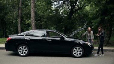 İki güzel kız yol kenarında durur ve açık motor kaputunun önünde tartışırlar, çünkü arabaları bozulmuştur ve ne yapacaklarını bilemezler.