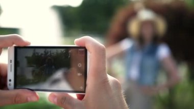 Adam akıllı telefonu elinde tutuyordu. Adam telefonda kızın fotoğrafını çekti. Gülümseyen ve poz veren kız.