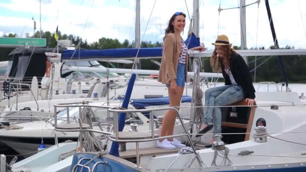 少女たちはヨットで話している 女の子たちは笑って笑っている 少女たちはヨットに招待するために手を振っている 女の子はどこかで手を示して笑顔 — ストック動画