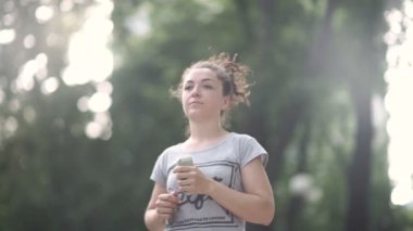 Güzel kıvırcık saçlı kadın yeşil parkta çalışan ve akıllı telefon bakmak