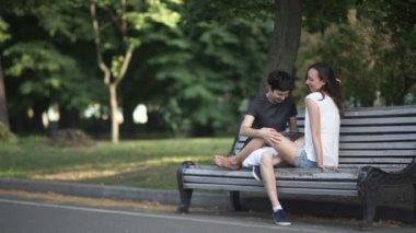 parkta bankta oturan iki güzel lezbiyen video, kadınların sarılma, tablet bakarak ve gülüyor