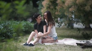 Ağacın altında parkta kapak oturan iki güzel lezbiyen, kamera bakarak lezbiyen çift öpüşme, video 