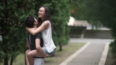 Yavaş çekim video, lezbiyenler parkta kandırıyorlar. Kızlardan biri kollarında kız arkadaşı tutuyor ve onunla arkalarını dön, kadın taşıyan, video 