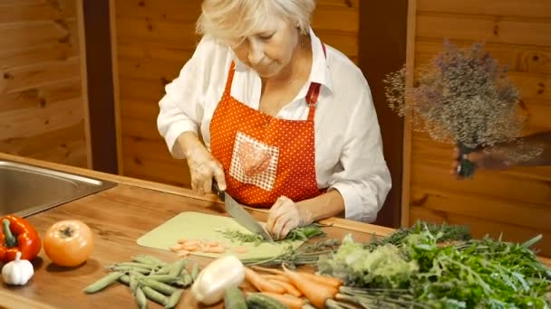 男子送花给他年迈的妻子 成熟的女人站在厨房 切蔬菜 — 图库视频影像