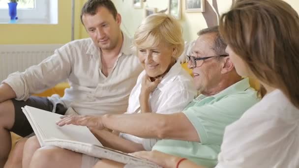 Χαρούμενη Οικογένεια Γελώντας Κάθεται Στον Καναπέ Και Βλέποντας Άλμπουμ Βίντεο — Αρχείο Βίντεο