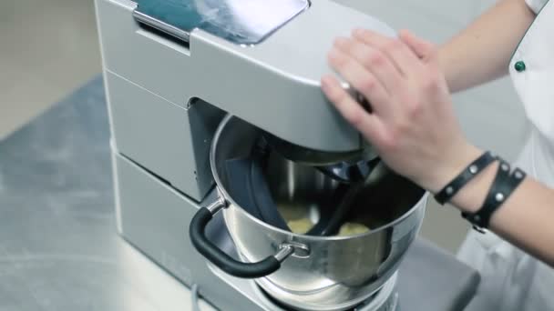 厨师把搅拌器放在一个碗里搅拌 人包括处理器 搅拌器开始把面团搅拌在一个碗里 照相机是搅拌的一大面团 搅拌速率的变化 一个人在厨房窗户的后面工作 后续行动 — 图库视频影像