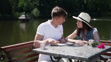 Nehir kenarındaki haritaya bakan çift. Adam kız arkadaşına nereye gideceğini gösterir. Kız memnun oldu ve erkek arkadaşının yanağından öptü. Kız oğlanı kucaklıyor..