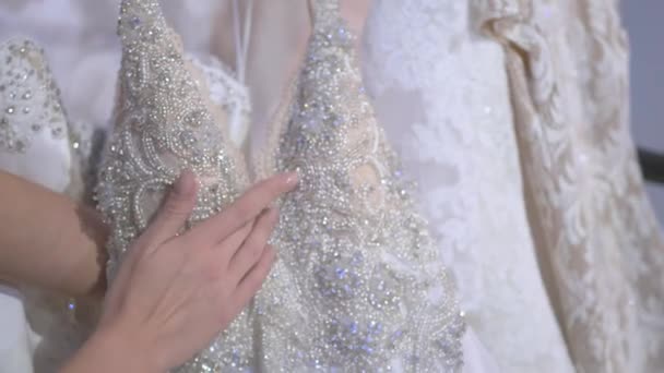 相机聚焦在白色婚纱上 照相机慢慢地沿着漂亮的婚纱上下移动 修指甲的女人的手小心翼翼地摸着华丽的婚纱 — 图库视频影像