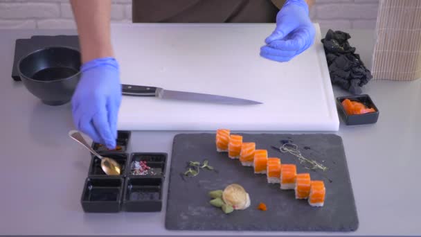 Zbliżenie Kucharz Przygotowuje Deskę Sushi Dostarczenia Kucharz Rękawiczkach Zdobiących Planszę — Wideo stockowe