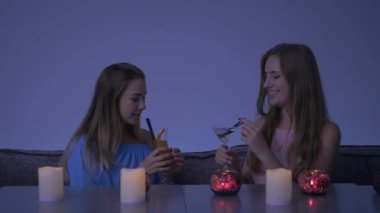 İki güzel kız kafede oturuyor ve eğleniyorlar. Sevimli arkadaşlar el ele tutuşup, kadeh tokuşturup kokteyl içiyorlar. Güzel genç kızlar kameraya bakıp gülüyorlar. Kamerada başparmak gösteren gülümseyen kızlar.