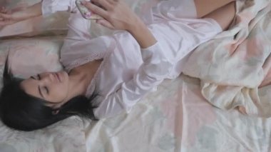 Yukarıdan ateş ediyorlar. Kamera, yatakta uzanıp dinlenen genç ve güzel bir kadına odaklanıyor. Akıllı telefonu elinde tutan güzel genç bir kadın saçına dokunur ve selfie çeker..