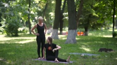 Kadınlar yeşil parkta yoga yapıyor.