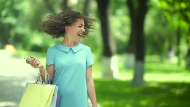 Curly Kvinna Går Med Shoppingväskor Parken — Stockvideo