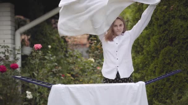 Cheerful funny cute young woman have fun singing and dancing enjoying rhythm at the backyard while doing house work with the linen. Washday, washing day. — Stock Video