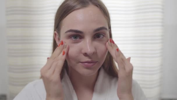 Beauty portrait of young woman with smooth healthy skin, she gently touches her face with her fingers. Cute girl with different colored eyes. Skincare and beauty concept. Real people series. — Stock Video