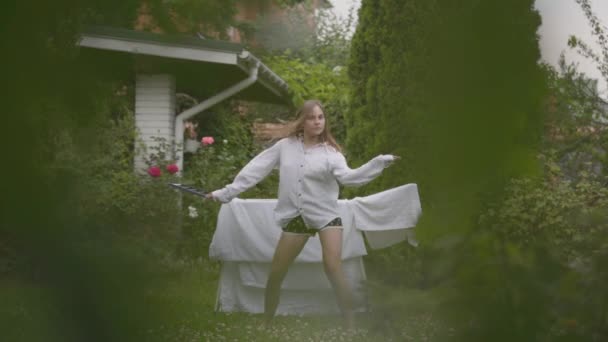 Charming caucasian young woman have fun singing and dancing at the backyard while doing house work with the linen. Washday, washing day. Slow motion. — Stock Video