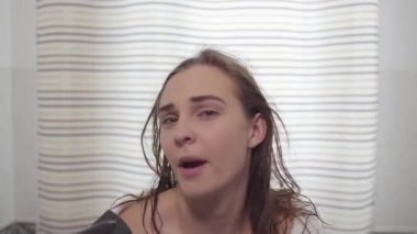 Sevimli genç beyaz beyaz kadın portre kamera bakarak ve saç kurutma makinesi ile saçlarını kurutma sırasında dans. Farklı renkli gözleri olan güzel bir kız. Vücut bakımı, saç bakımı, güzellik konsepti.