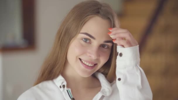 Retrato de mujer sonriente hermosa y despreocupada con diferentes ojos de colores mirando a la cámara en el interior. Feliz mujer caucásica saluda nuevo día. Ocio, día libre en casa. Serie de personas reales . — Vídeos de Stock