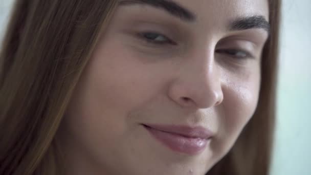 Retrato de cerca de una linda mujer joven con ojos de diferentes colores mirando a la cámara por la mañana. Feliz mujer caucásica saluda nuevo día. Ocio, día libre en casa. Serie de personas reales . — Vídeo de stock