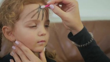 Kıvırcık kızı Cadılar Bayramı partisine hazırlayan kadının videosu. Kadın yüzü makyaj yapar.
