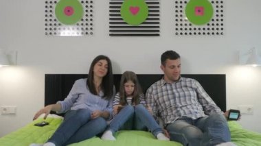 Yatak odasında büyük yeşil bir yatakta yatan genç bir aile. Çekici bir adam ve güzel bir kadın akıllı telefon kullanır, küçük kız tablet kullanır. Aileler aletlerini bir kenara bırakıp kızlarına sarılıyorlar. Kız gülümsüyor, ailesine sarılıyor ve kameraya bakıyor..